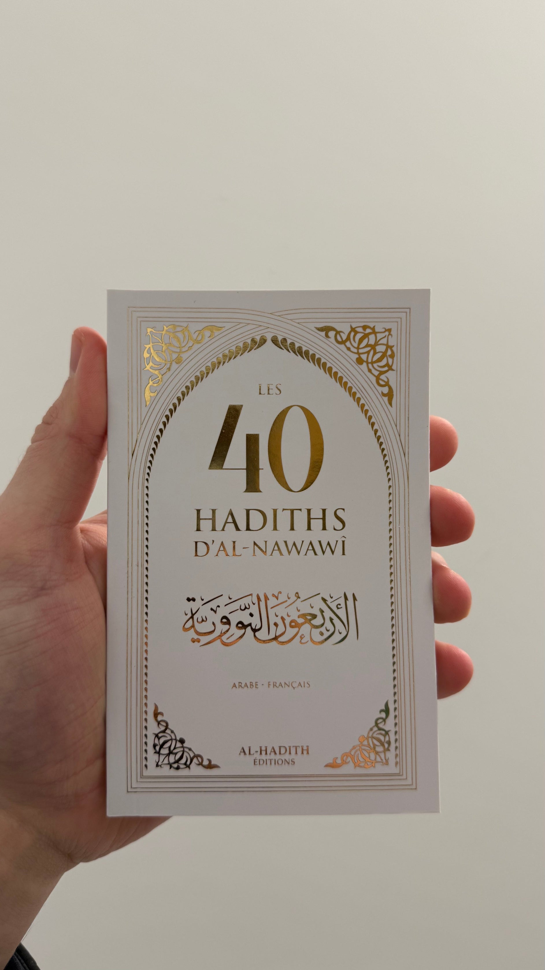 livre blanc de hadiths de l'imam Al-Nawawi de l'édition Al-Hadith tenu dans une main