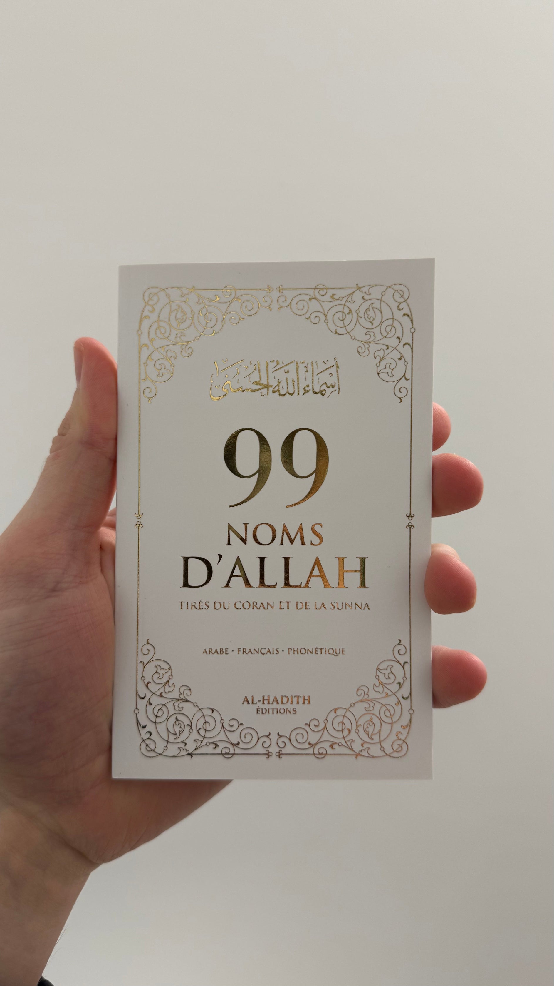 Livre blanc sur les 99 noms d'Allah de l'édition Al-Hadith tenu dans une main
