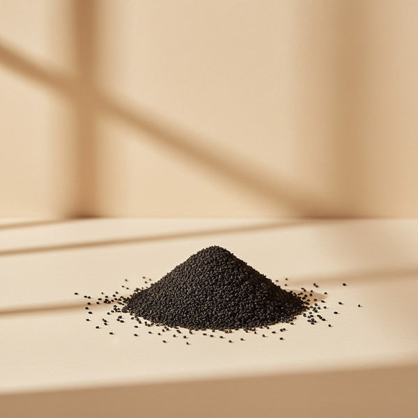 Petit tas de graines de nigelle (Habbatul Baraka) noires et pures sur un fond neutre, superaliment naturel aux multiples bienfaits santé.